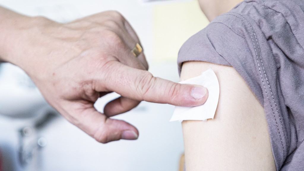 Foto: Ein Kinder- und Jugendarzt drückt einen Tupfer an die Impf-Stelle am Arm einer jungen Frau. 