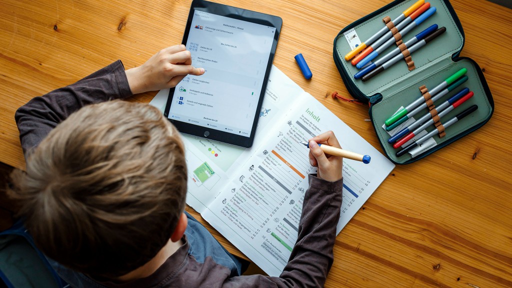 Ein Schüler lernt mit Tablet und Arbeitsheft