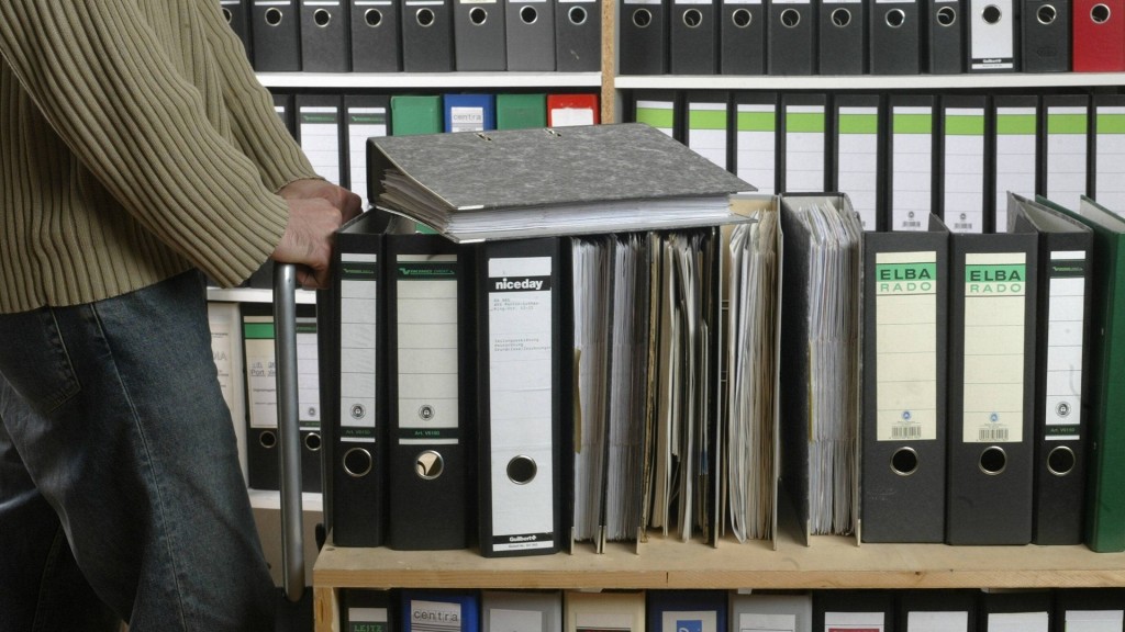 Eine Person schiebt Aktenberge einen Aktenschrank entlang