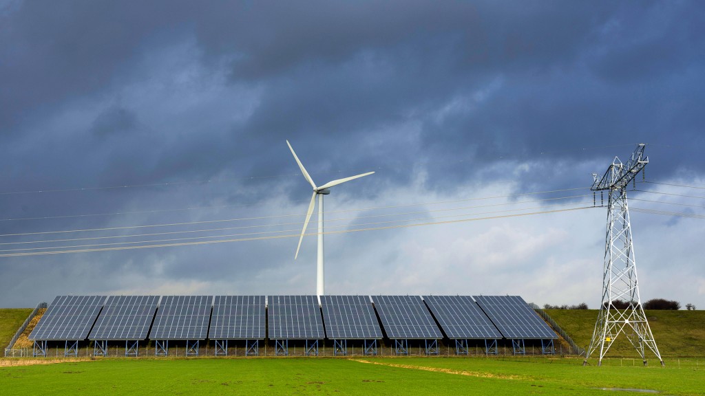 Stromleitungen laufen über einer Solaranlage vor einem Windrad