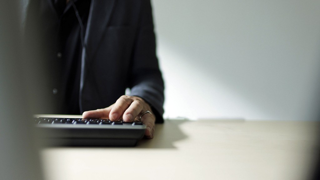 Foto: Ein Mann steht am Schreibtisch vor einem Computer