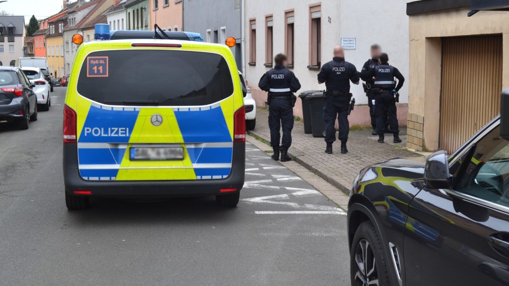 Polizeieinsatz in der Innenstadt von Neunkirchen. Polizisten stehen neben dem Einsatzfahrzeug.