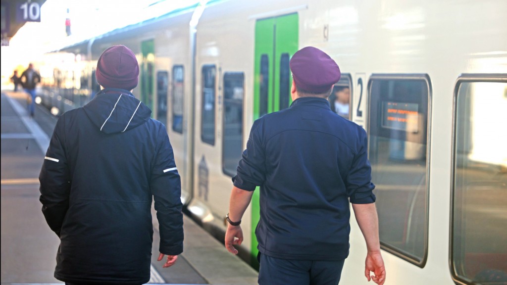 Zwei Bahnmitarbeiter gehen einen Bahnsteig entlang.