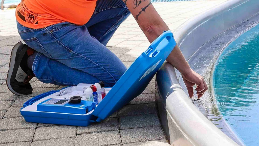 Symbolbild: In einem Freibadbecken wird eine Wasserprobe genommen