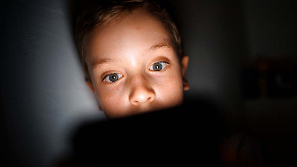  Ein Kind schaut im Dunkeln auf das Display eines Smartphones