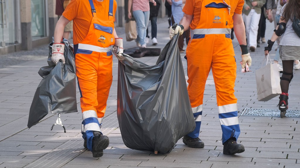 Zwei Angestellte der Abfallentsorgung beim Transportieren eines Müllbeutels