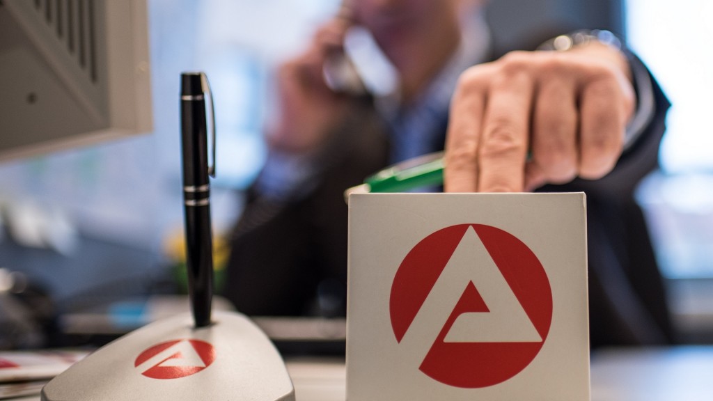 Ein Mann sitzt in der Bundesagentur für Arbeit. Notizblock und Stifthalter mit Logo der Agentur auf dem Schreibtisch.