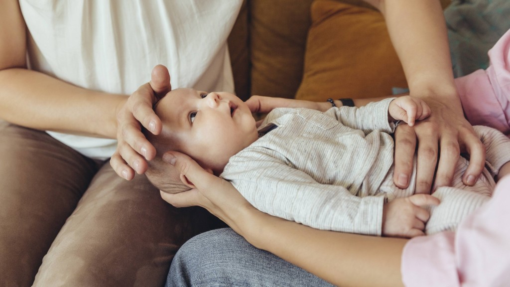 Eine Hebamme zeigt einer jungen Mutter wie sie Ihr Baby massiert.