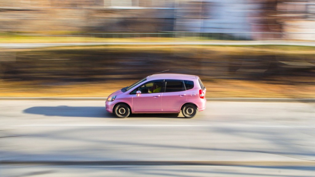 Kleinwagen in rosa fährt auf Straße