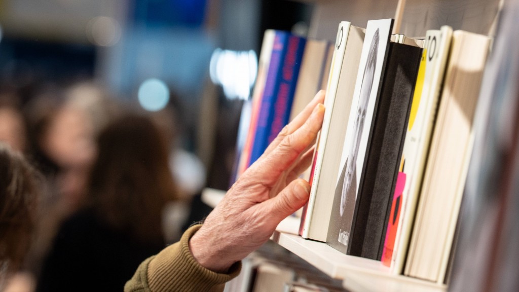 Foto: Jemand greift nach einem Buch in einem Bücherregal