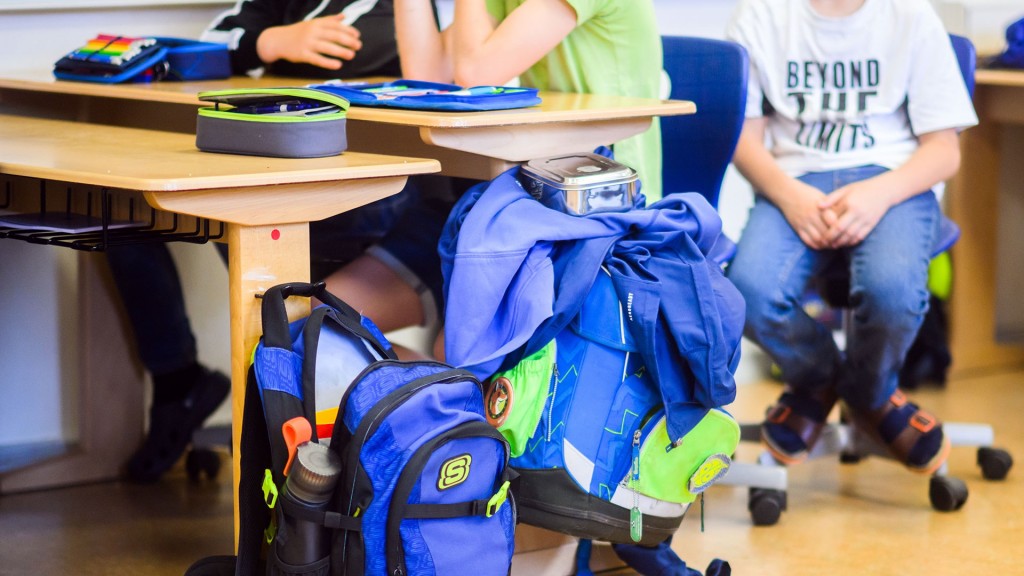 Rucksäcke stehen neben Grundschülern in einer Klasse 