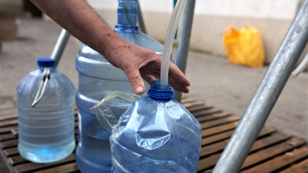 Ein Mann füllt an einer Wasserstelle in mehrere Plastikflaschen Wasser ab.