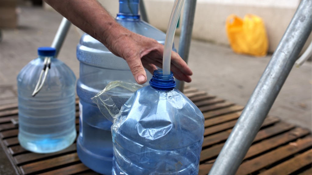 Foto: Ein Mann füllt an einer Wasserstelle in mehrere Plastikflaschen Wasser ab.