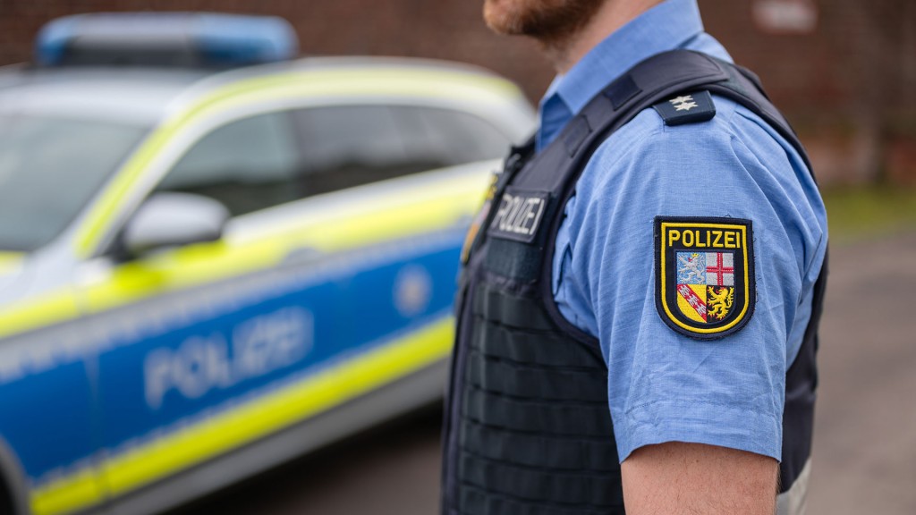 Foto: Ein Polizist steht vor seinem Einsatzfahrzeug