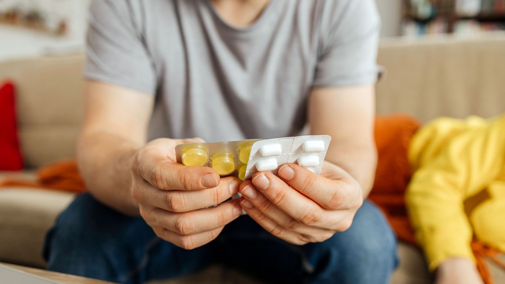 Ein Mann sitzt mit Tabletten-Streifen auf dem Sofa