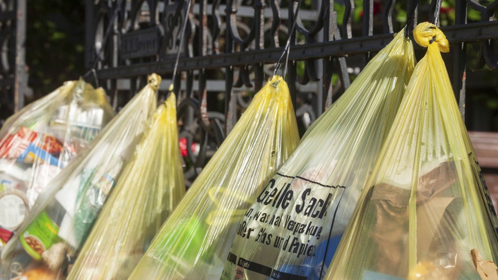 Gelbe Säcke für Plastikmüll, hängen an Gartenzaun vor einem Hauseingang