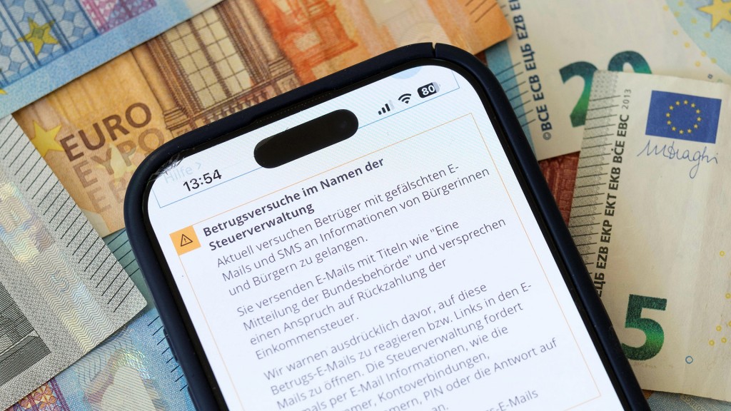 Symbolbild: Ein Smartphone mit Warnmeldung vor falschen Nachrichten der Steuerverwaltung liegt auf Euro-Banknoten