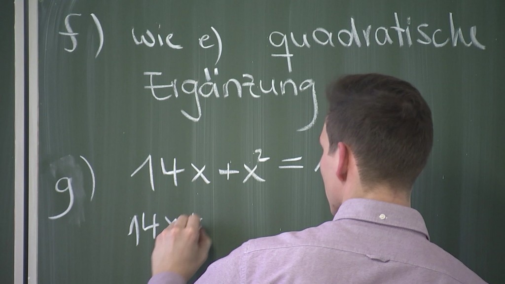 Foto: Mann schreibt mathematische Gleichungen an eine Tafel