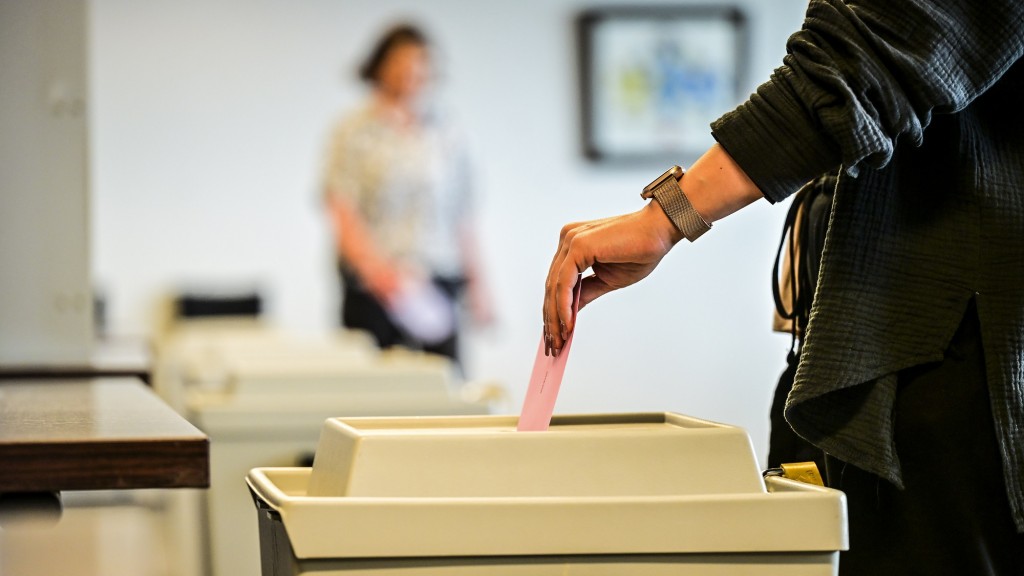 Foto: Eine Person wirft ihren Stimmzettel in eine Wahlurne in einem Wahlbüro