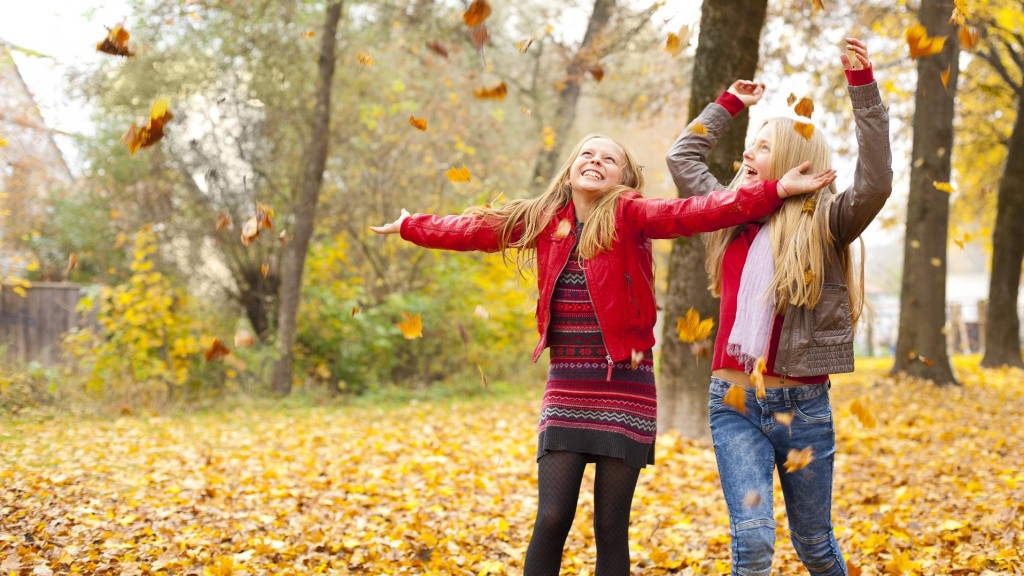 Kinder spielen mit Herbstlaub.