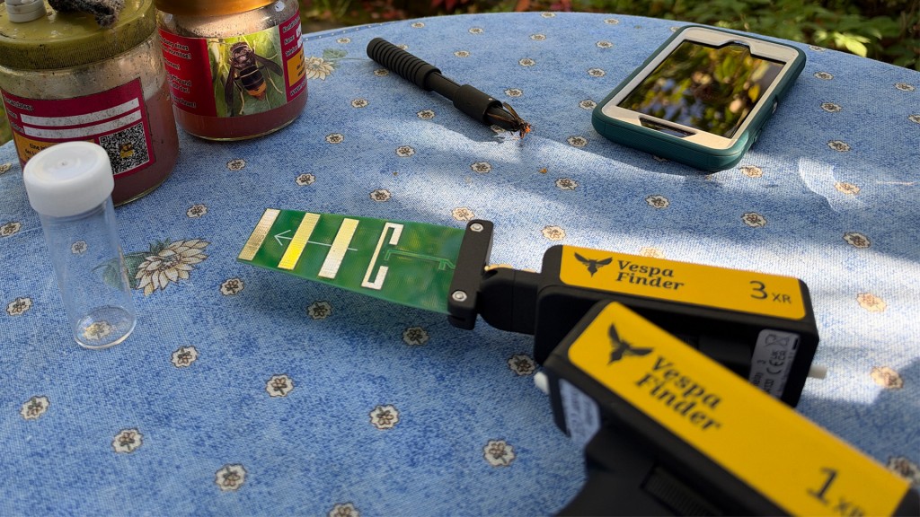 Ein Tisch mit zwei Ortungsgeräten für die Peilsender, einem Greifwerkzeug, zwei Locktöpfen für Hornissen und einem Handy.