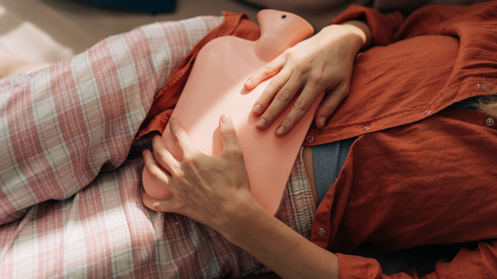 Eine Frau mit einer Wärmflasche auf dem Bauch