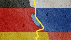 Bildbeschreibung: (Fotomontage) Die deutsche und die russische Flagge auf einem rissigen Steinhintergrund