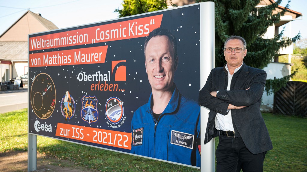Der Oberthaler Bürgermeister Stephan Rausch neben dem Plakat von Matthias Maurer. (Foto: picture alliance/dpa | Oliver Dietze)