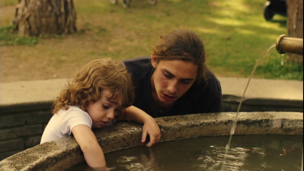 Foto: Ein junger Vater mit seinem Kind an einem Brunnen