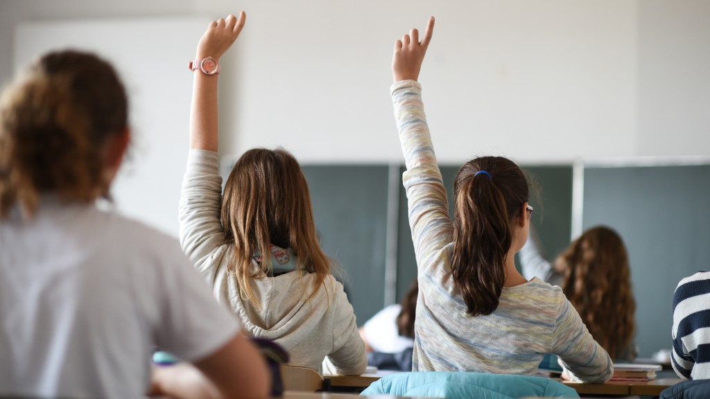 Schülerinnen strecken während des Deutschunterrichts in einem Gymnasium ihre Hände nach oben.