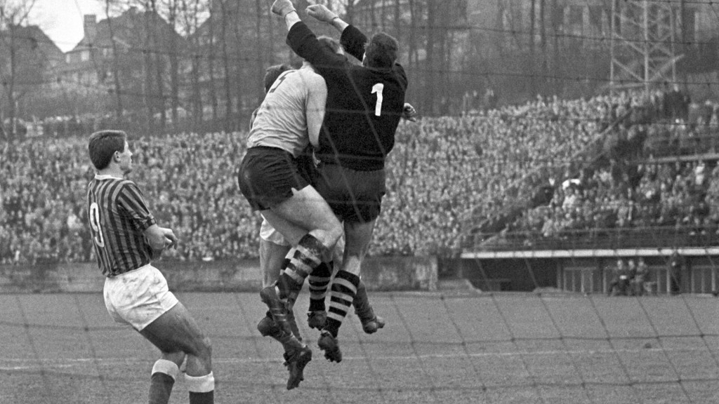 Fußball 1. Bundesliga, Saison 1963/64: 1. FC Saarbrücken gewinnt gegen Borussia Dortmund 2:1 in Saarbrücken am 30. April 1964. Dortmunds Torwart Heinrich 'Heini' Kwiatkowski (rechts) klärt, links Saarbrückens Jürgen Kraftczyk.