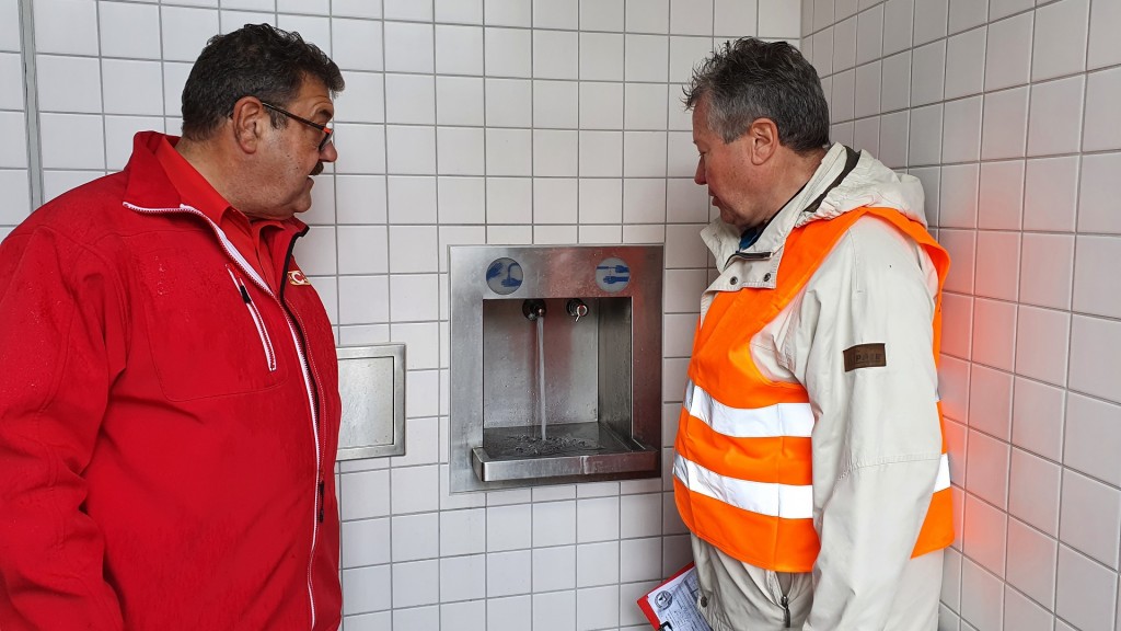 Volker Schorke und Heinz Jung kontrollieren den Wasserhahn auf einer Rastplatz Toilette