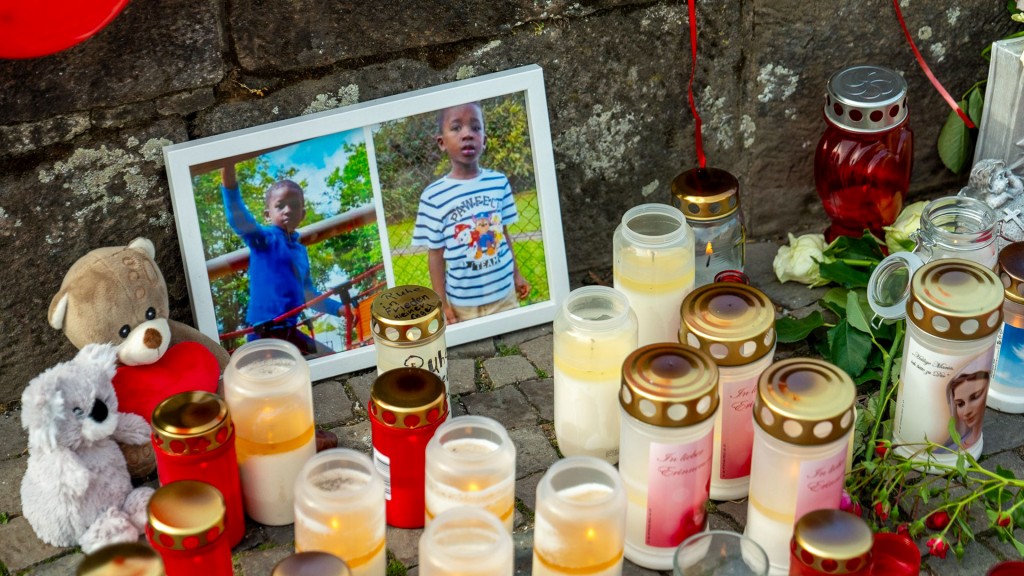 Trauer um Mathis, Kerzen stehen auf dem Boden vor Bildern des Jungen