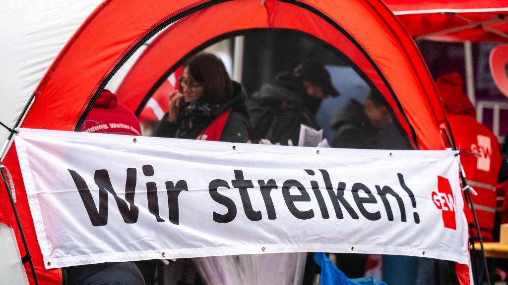 Ein Banner mit der Aufschrift „Wir streiken!“ ist am Stand der Gewerkschaft Erziehung und Wissenschaft (GEW)