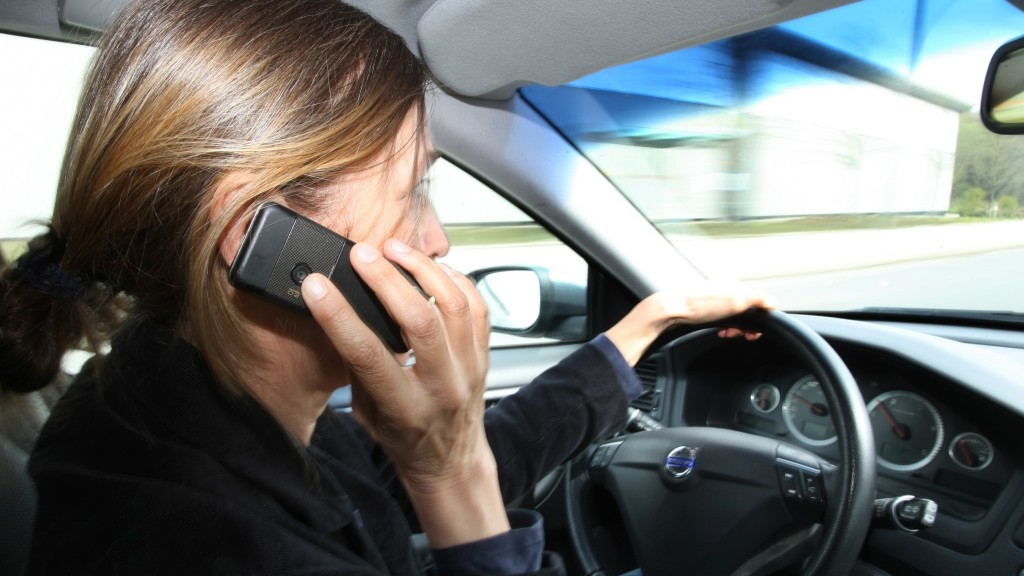 Eine Frau telefoniert während der Fahrt mit ihrem Handy.