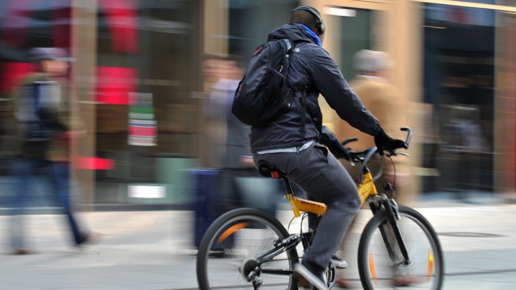 Ein Radfahrer fährt mit Kopfhörern durch eine Fußgängerzone 