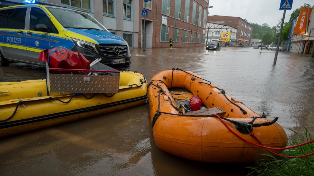 Schlauchboote liegen bereit an der Absperrung der Polizei der überschwemmten Straße in Saarbrücken-Rußhütte.