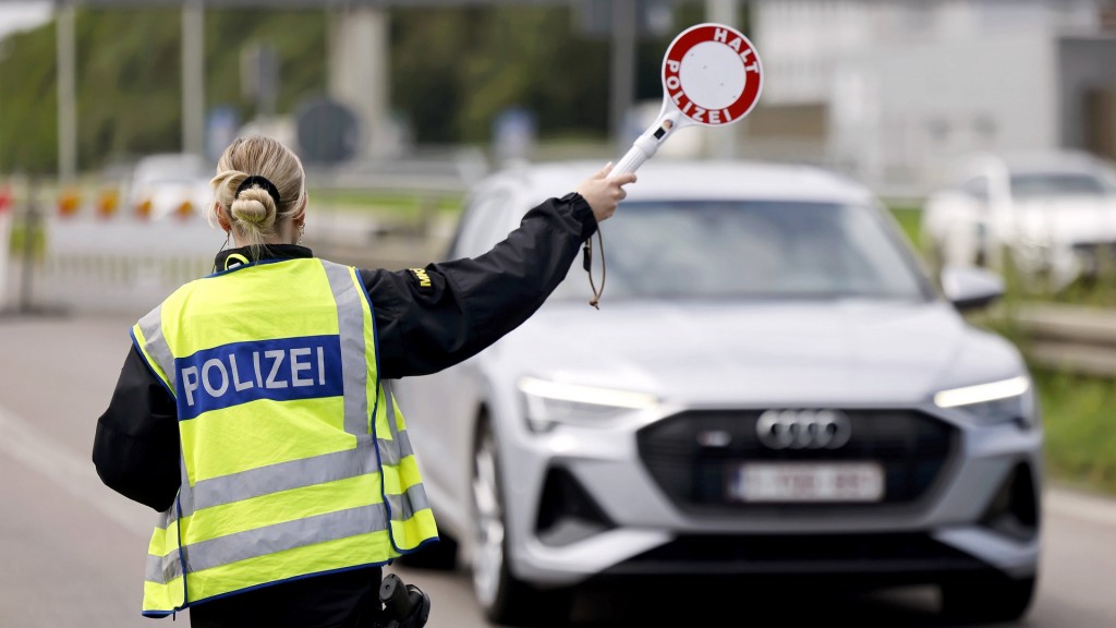 Polizisten kontrollieren Fahrzeuginsassen und Papiere bei der Einreise nach Deutschland