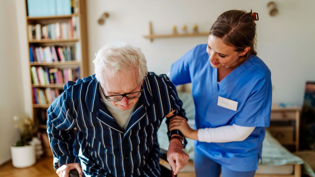 Foto: Eine Altenpflegekraft hilf einem Pflegeheimbewohner aus dem Rollstuhl