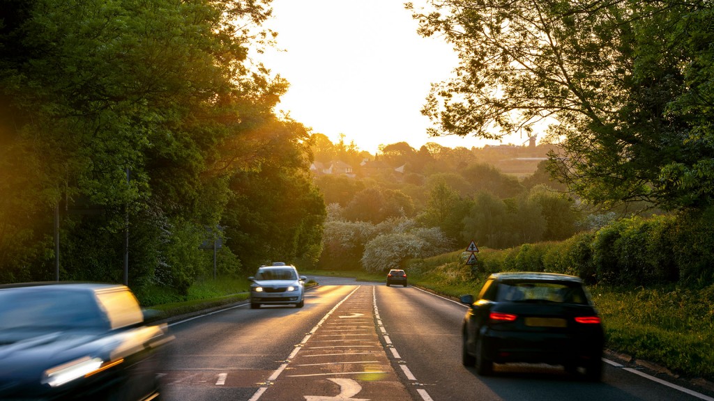 Autos fahren auf einer Landstraße bei tiefstehender Sommersonne