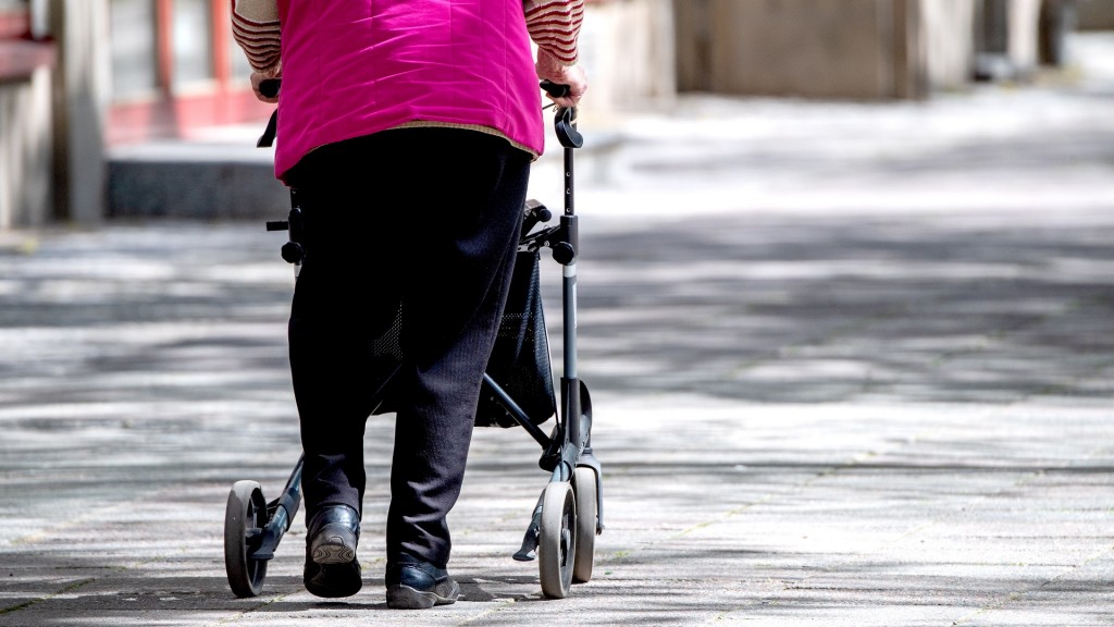 Eine Seniorin geht mit ihrer Gehilfe über einen leeren Platz