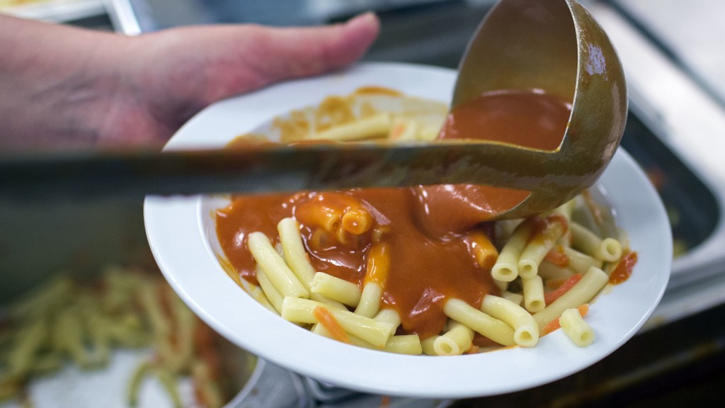 Mit einer Kelle wird das Essen auf Teller verteilt.