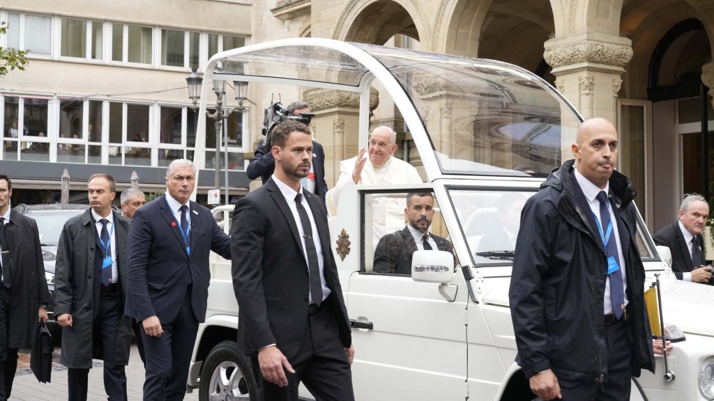 Papst Franziskus fährt mit dem Papamobil begleitet von Leibwächtern