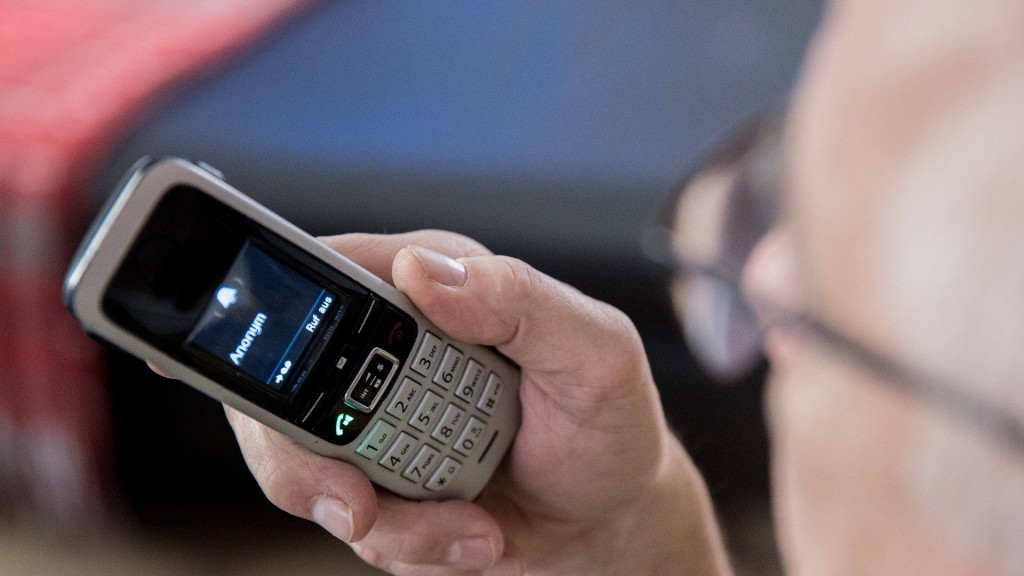 Foto: Ein älterer Menschen sitzt in seiner Wohnung und hält ein Telefon in der Hand.