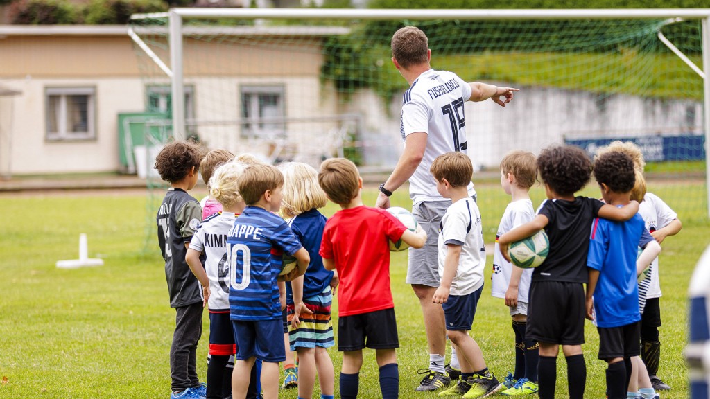 Ein ehrenamtlicher Trainer trainiert Kinder auf dem Fussballplatz