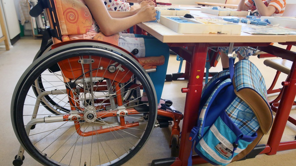 Eine Schülerin sitzt im Klassenzimmer in ihrem Rollstuhl.