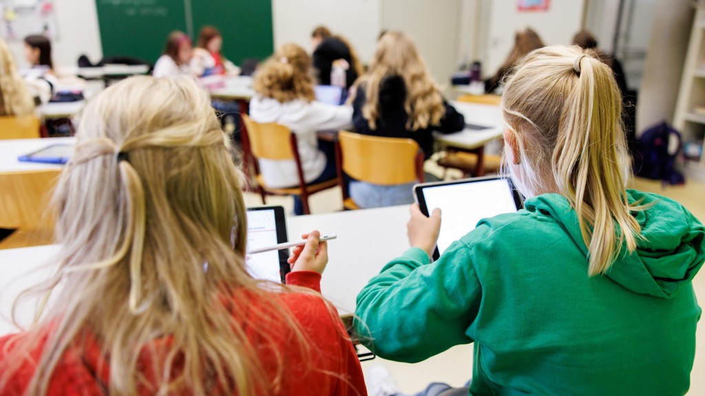 Ein Mädchen sitzt mit Schulsachen vor einem Laptop