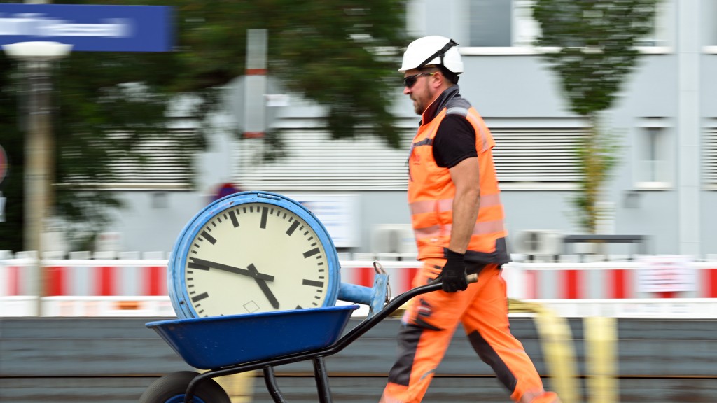 Ein Arbeiter transportiert eine Bahnhofsuhr auf einer Schubkarre ab