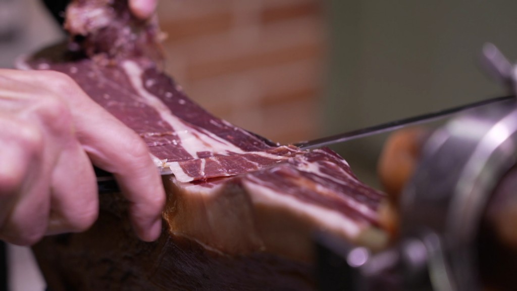 Foto: Eine Person schneidet Iberico-Schinken dünn 