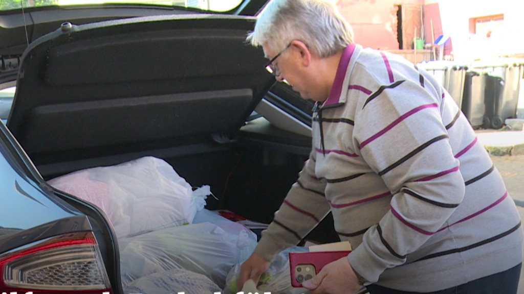 Foto: Mann packt Kleidersäcke ins Auto